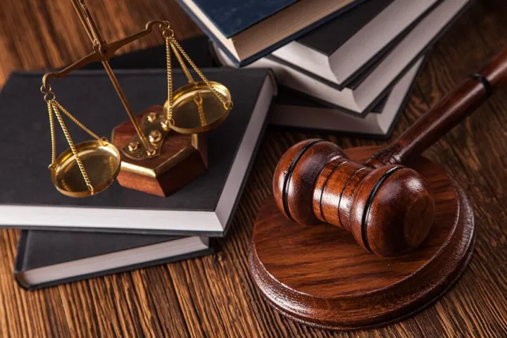 A judge mallet, empty court weighing scale and books on table