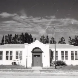 One story old school house with trees behind it