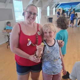 Smiling woman and boy holding up crafts