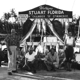 Fishermen and women with their catch in from of Welcome to Stuart Florida sign