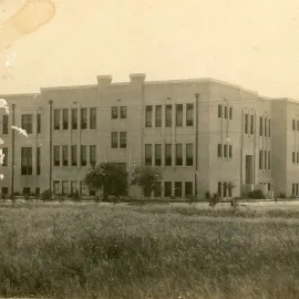 Three story school building by field